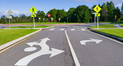 Cluster of street signs and road markings at an entrance to a loop